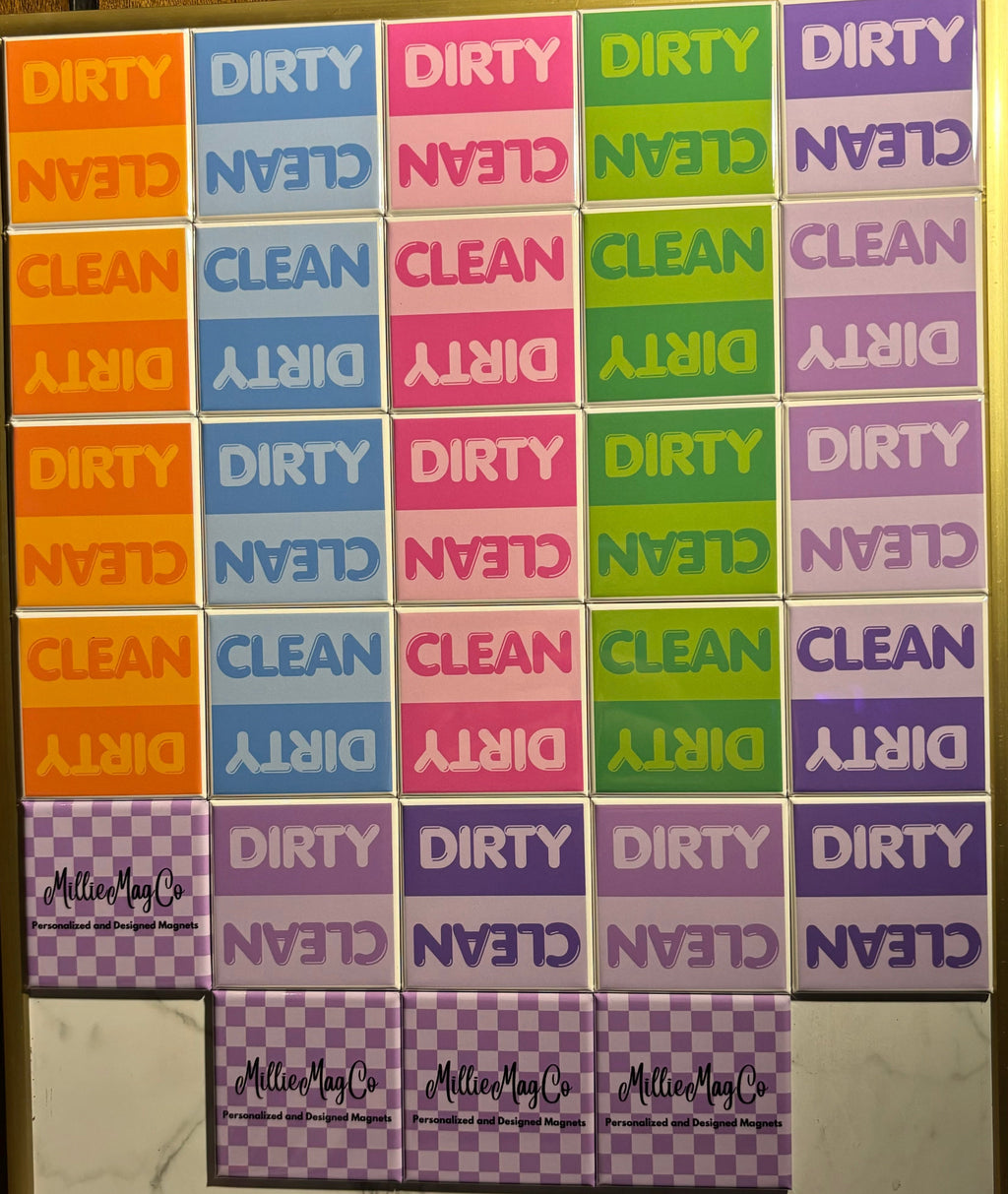 Sets of 'Clean' and 'Dirty' Dishwasher Magnets by Millie in various colors on a magnetic board